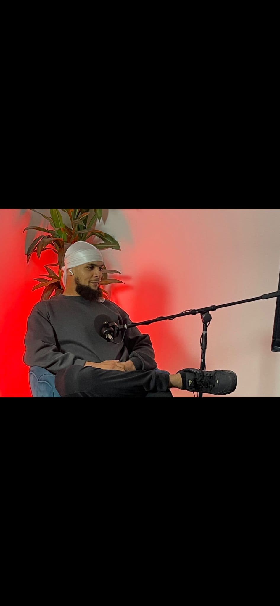 Zayd seated at a microphone in a recording studio