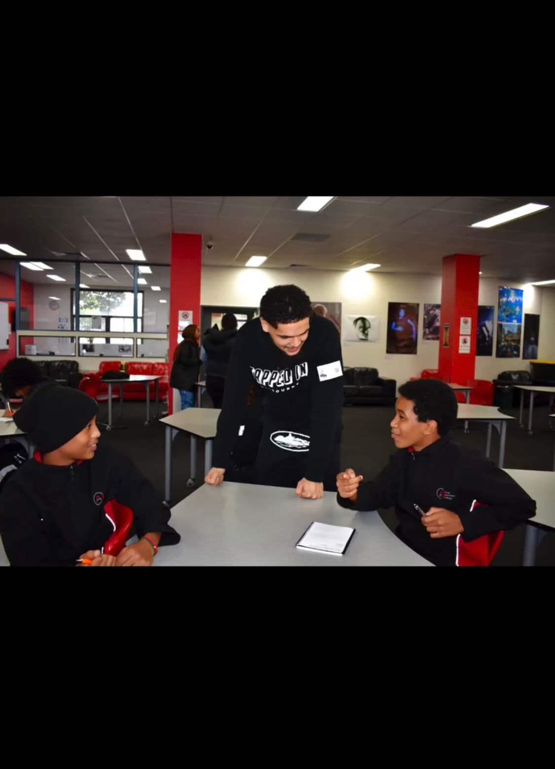 Zayd talking with two students in a school common room