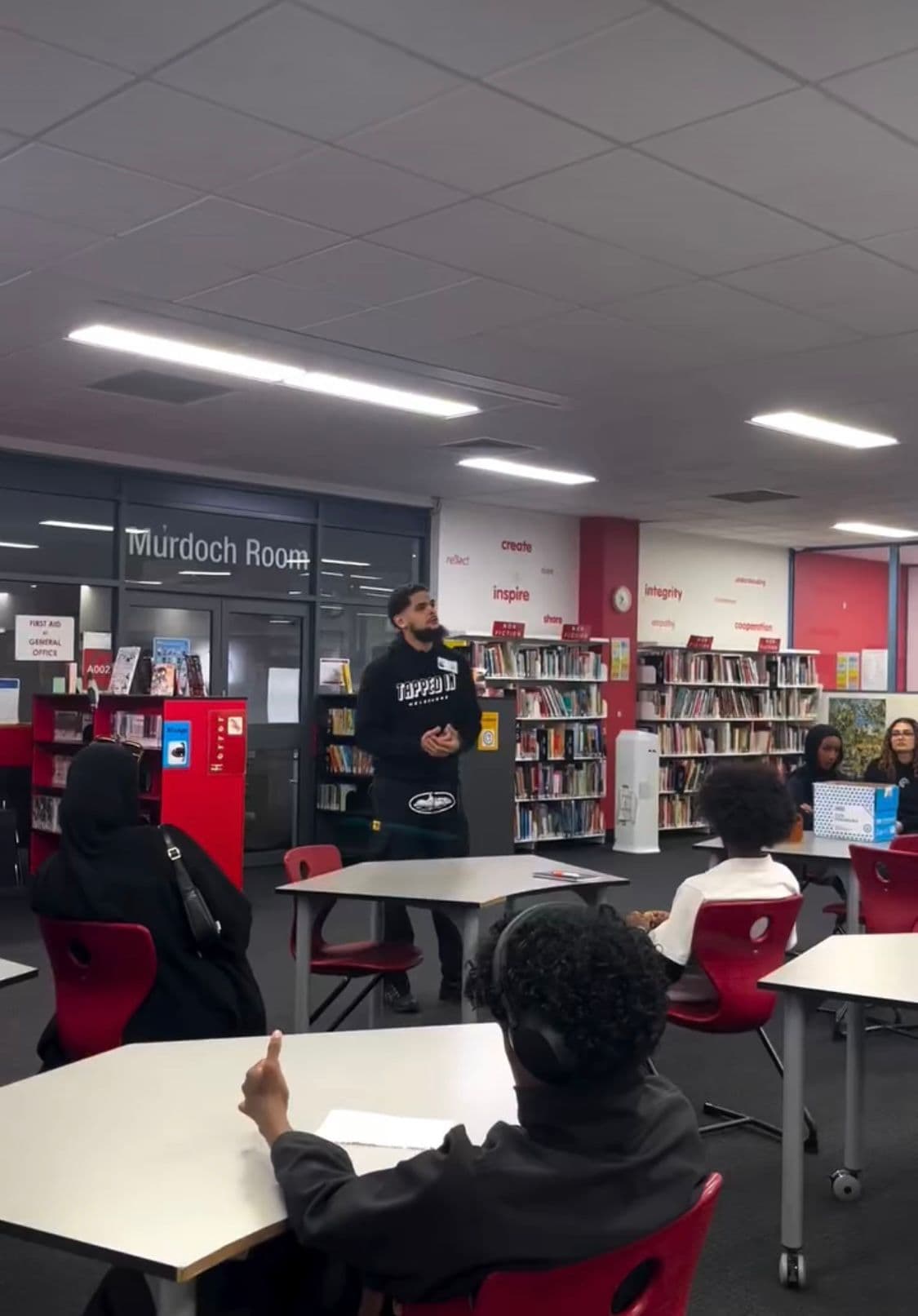 Zayd addressing seated students in a school library